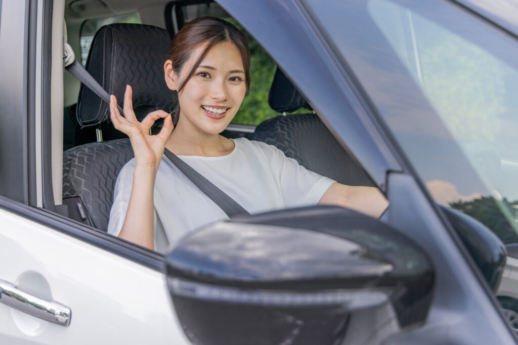 車に乗った女性がOKマークをしている画像